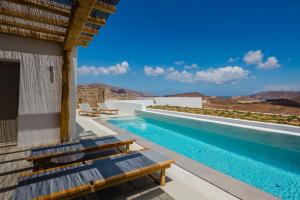 a pool with chairs and a view of the mountains at Amarelo Suites in Klouvas