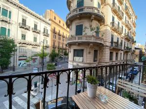 einen Balkon mit einem Holztisch vor einem Gebäude in der Unterkunft AQUAROOMS Luxury Suites in Palermo