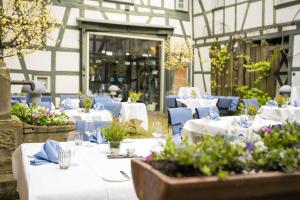 un restaurante con mesas blancas, sillas azules y flores en Restaurant & ****Hotel HÖERHOF, en Idstein