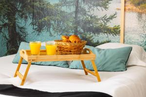 a basket of bread and two glasses of orange juice on a table at Studio élément - Eau in Saint-Aignan