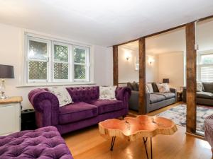 a living room with a purple couch and a table at Oakapple Cottage in Lyndhurst