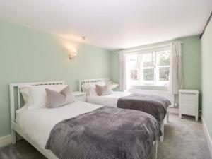 two beds in a bedroom with a window at Oakapple Cottage in Lyndhurst