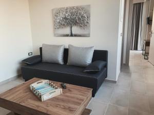 sala de estar con sofá negro y mesa en King Crimson Luxury Apartments, en Marathokefála