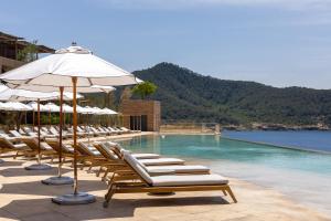a swimming pool with lounge chairs and umbrellas at Six Senses Ibiza in Portinatx