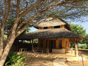 ein kleines Haus mit einem Strohdach und einer Bank in der Unterkunft Mangrove House in Lamu