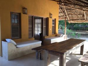 une terrasse couverte d'une maison avec une table et des chaises en bois dans l'établissement Mangrove House, à Lamu