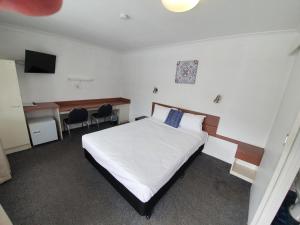 
a bedroom with a white bed and white walls at Metro Motel Rockhampton in Rockhampton
