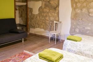 a room with two beds and a chair and a wall at Casa Rural La Fàbrega in Aiguamurcia