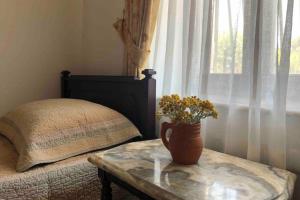 a table with a vase of flowers on it next to a bed at A summer house is close to the sea with a garden in Fethiye