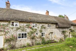 an old stone house with a thatched roof at Willow Cottage in Chilmark