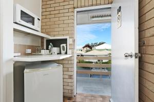 a kitchen with a microwave and a sink at Wunpalm Motel & Holiday Cabins in Maroochydore