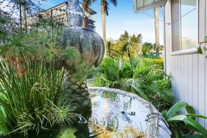 un jardín con una mesa y un estanque de peces en Wunpalm Motel & Cabins - Late check-in available, en Maroochydore