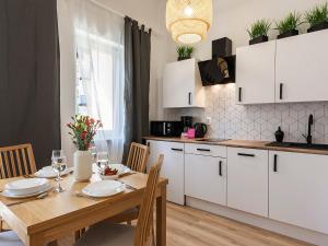 VacationClub - Olymp Apartment 502A في كولوبرزيغ: مطبخ مع طاولة خشبية ودواليب بيضاء