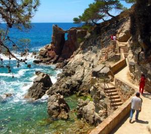 un grupo de personas caminando por una playa rocosa en Villa Mar i Cel con jacuzzi, en Tossa de Mar