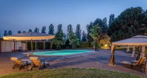 einen Pool mit Stühlen und Sonnenschirmen im Hof in der Unterkunft Palazzo Cavagna Sangiuliani in Bereguardo