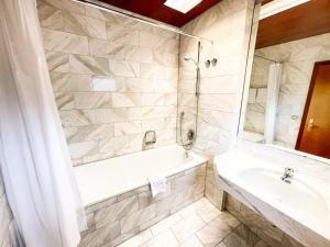 ein Badezimmer mit einer Badewanne, einem Waschbecken und einem Spiegel in der Unterkunft Gästehaus Sophienstraße in Stuttgart