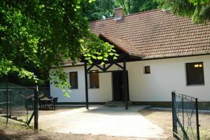 a white house with a gate in front of it at Forest gate Vendégház in Mátraszentimre