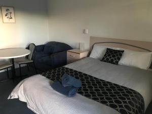 a bedroom with a bed and a couch and a table at County Lodge Motor Inn in West Wyalong