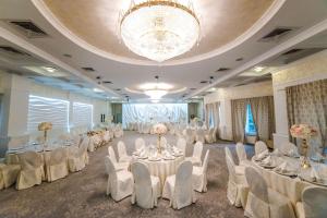 a banquet hall with white tables and chairs and a chandelier at Best Lido Hotel in Timişoara +161 photos