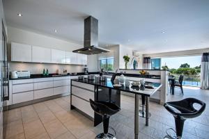 a kitchen with white cabinets and black counter chairs at Vista Mar by Algarve Villa Holidays in Sesmarias
