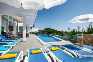 a row of blue and white lounge chairs next to a swimming pool at Vista Mar by Algarve Villa Holidays in Sesmarias