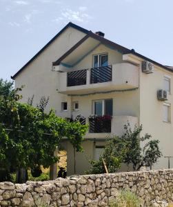 a white house with balconies and a stone wall at Apartments Markovi Konaci in Trebinje