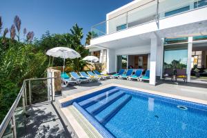 a villa with a swimming pool with chairs and an umbrella at Vista Mar by Algarve Villa Holidays in Sesmarias