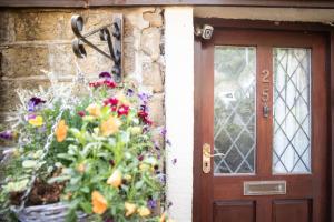 drzwi wejściowe domu z kwiatami w obiekcie Clay Well Cottage w mieście Huddersfield