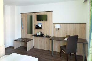 a room with a desk and a chair and a television at Hotel Blauer Karpfen in Oberschleißheim