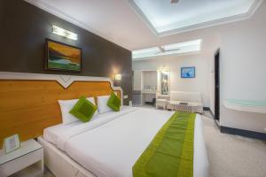 a bedroom with a large white bed with green accents at Treebo Trend Green View in Kolkata