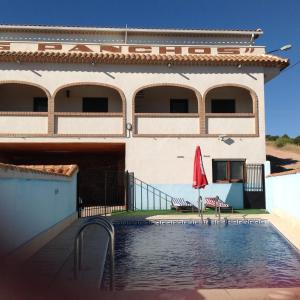 a house with a swimming pool in front of a building at Apartamentos Los Panchos in Ruidera