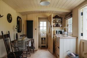 a small kitchen with a table and a microwave at The Shepherds Huts at Ormesby Manor in Ormesby Saint Michael