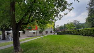ein grüner Hof mit einem Baum und einem gelben Gebäude in der Unterkunft Park Hotel Fantoni in Tabiano