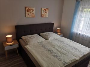 ein Bett in einem Schlafzimmer mit zwei Lampen an Tischen in der Unterkunft FERIENWOHNUNG SILBERG in Dörrenbach