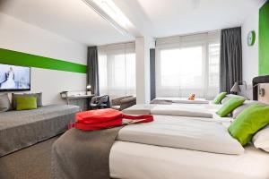 a hotel room with three beds with green accents at NunoHotel in Cologne