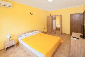 a yellow bedroom with a bed and a television at Апартамент Слънчев Ден in Balchik