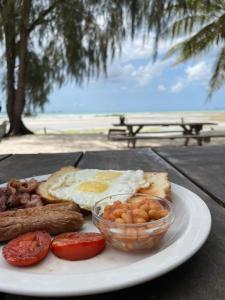 a plate of breakfast food with eggs sausage and tomatoes at Mikadi Beach Camp & Backpackers in Dar es Salaam