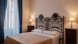 een slaapkamer met een groot bed en 2 nachtkastjes bij Palazzo dei Pavoni, Relais di Charme in LʼAquila