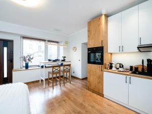 una cocina con armarios blancos y una mesa con sillas. en Apartament DeLux Aleja NMP 8 - Free parking en Częstochowa