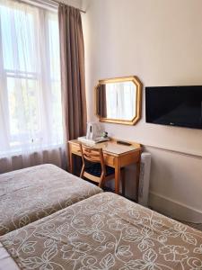 a hotel room with a bed and a desk with a mirror at Rushmore Hotel in London