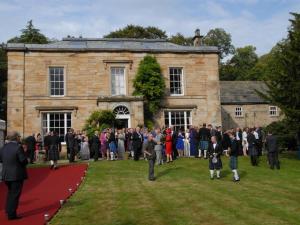 un grande gruppo di persone che si trovano di fronte a un edificio di Burnhopeside Hall a Lanchester