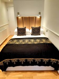 una camera da letto con un grande letto con lenzuola e cuscini neri di Rushmore Hotel a Londra
