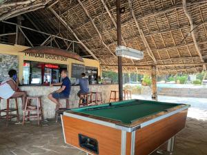 una mesa de billar frente a un bar con gente en Mikadi Beach Camp & Backpackers, en Dar es Salaam