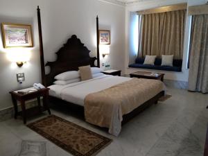 ein Hotelzimmer mit einem großen Bett und zwei Fenstern in der Unterkunft Fateh Garh Resort by Fateh Collection in Udaipur