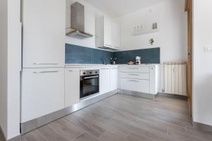a white kitchen with white cabinets and a wooden floor at A Casa di Lelia in Muggia
