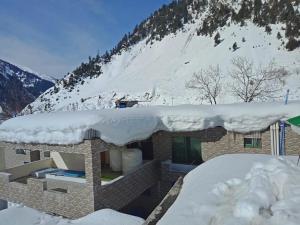 a building covered in snow with a mountain in the background at Hotel Mi-Amore in Naran