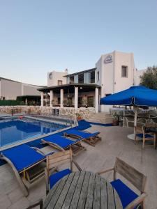 a resort with a pool and blue umbrellas and tables at Eden Hotel in Bodrum City