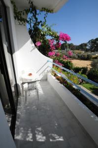 a white chair sitting on a balcony with pink flowers at HOTEL TINA FLORA in Kolymbia