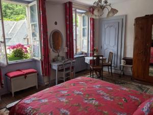 a bedroom with a bed and a table and windows at Sweeting's B & B Chailland in Chailland