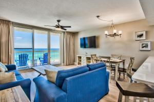 a living room with a blue couch and a dining room with a view at Pelican Beach Resort Destin in Destin